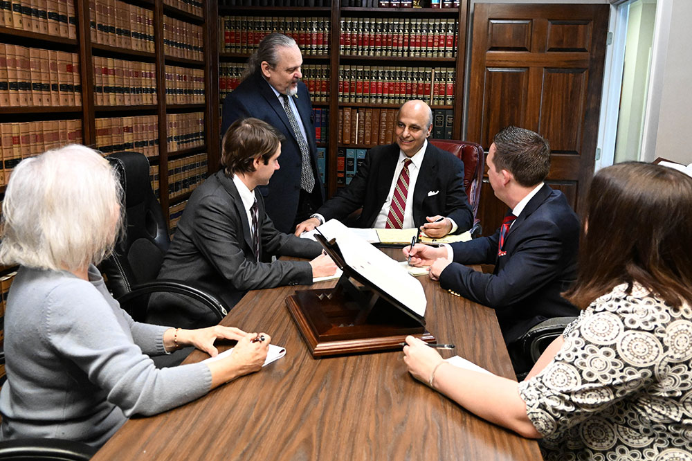 The firm's team sitting around conference table, surrounding by law books